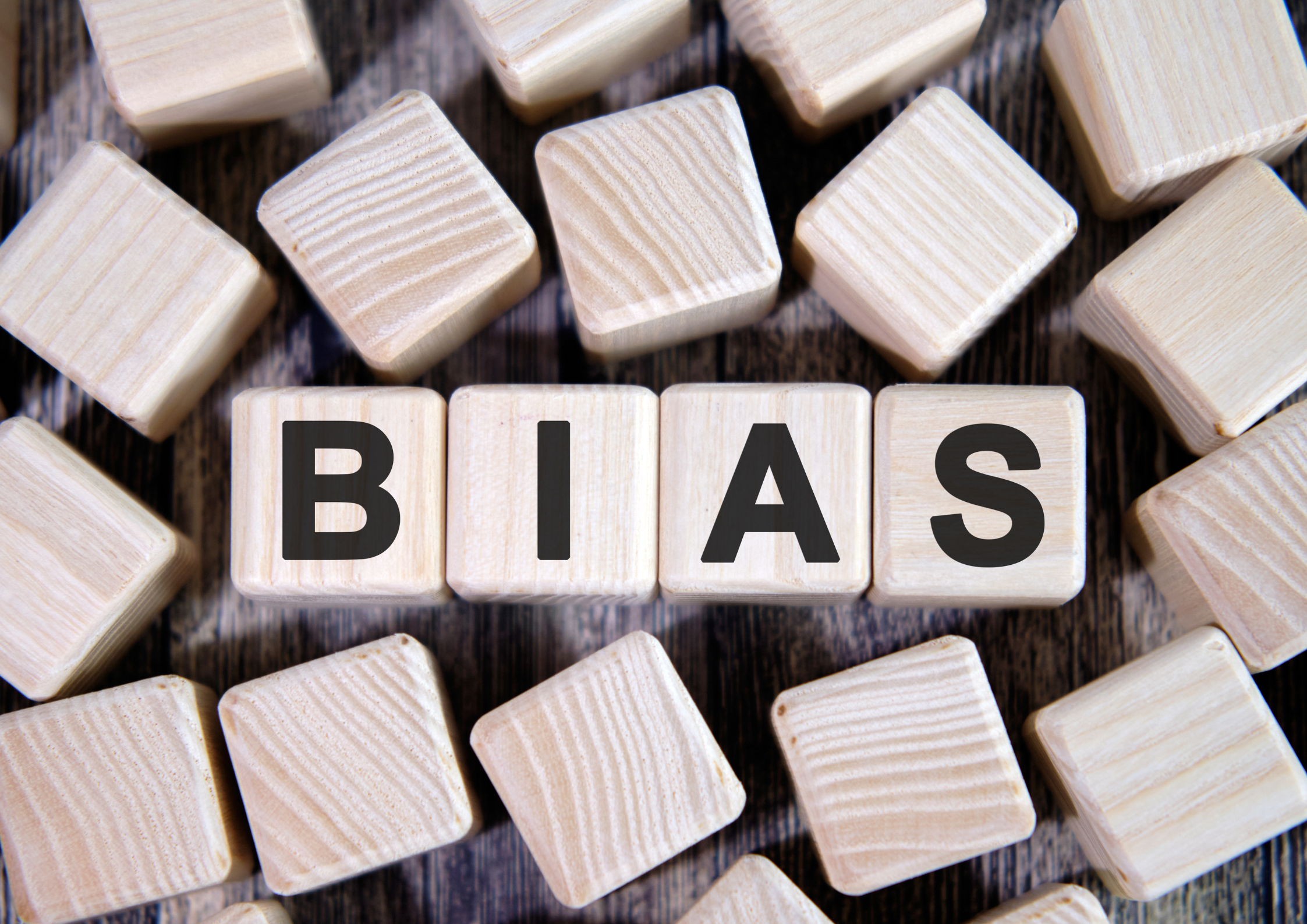 scattered wooden bricks, with 4 in the centre that spell the word bias.