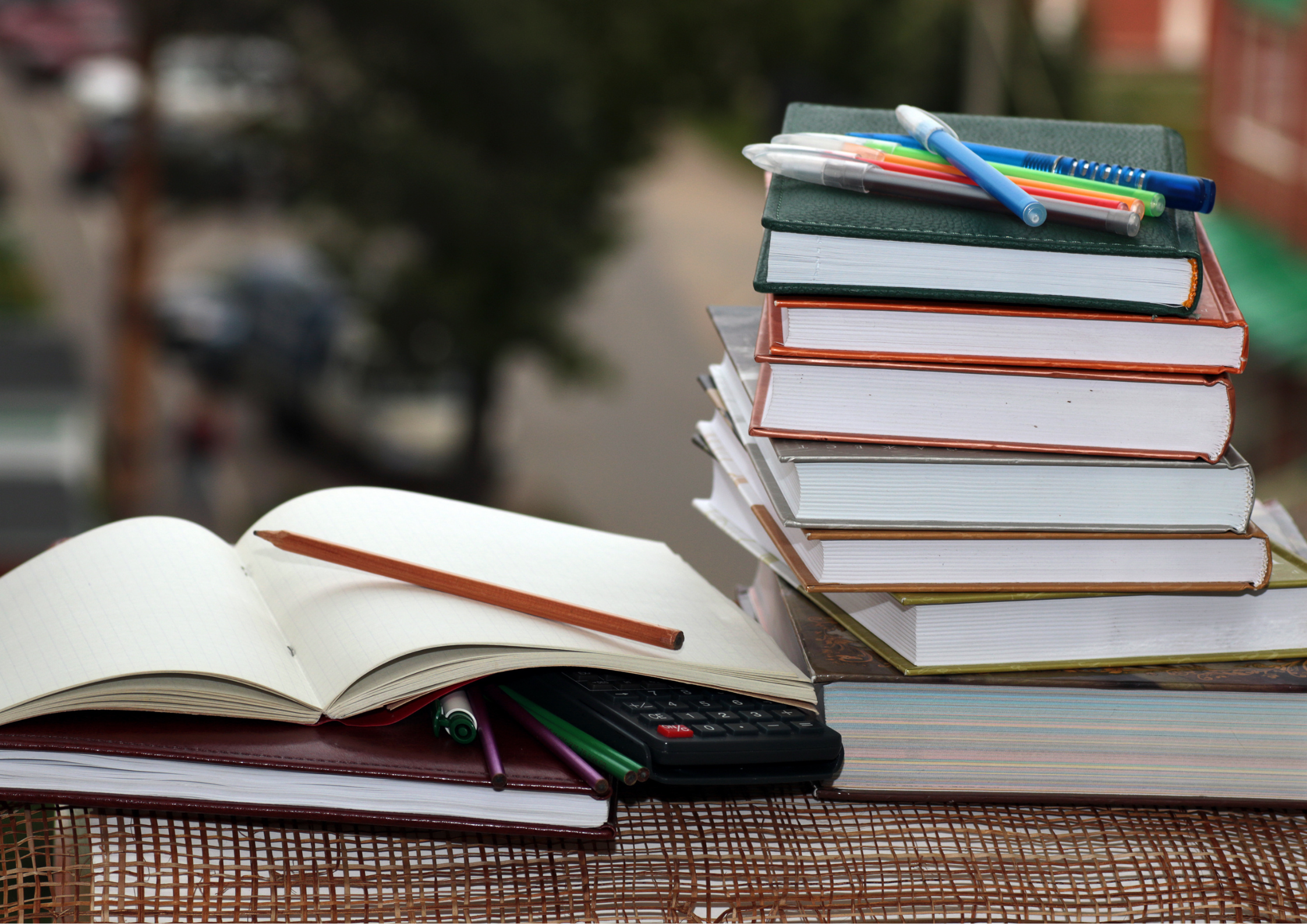 Stack of books and stationery, indicating someone studying.