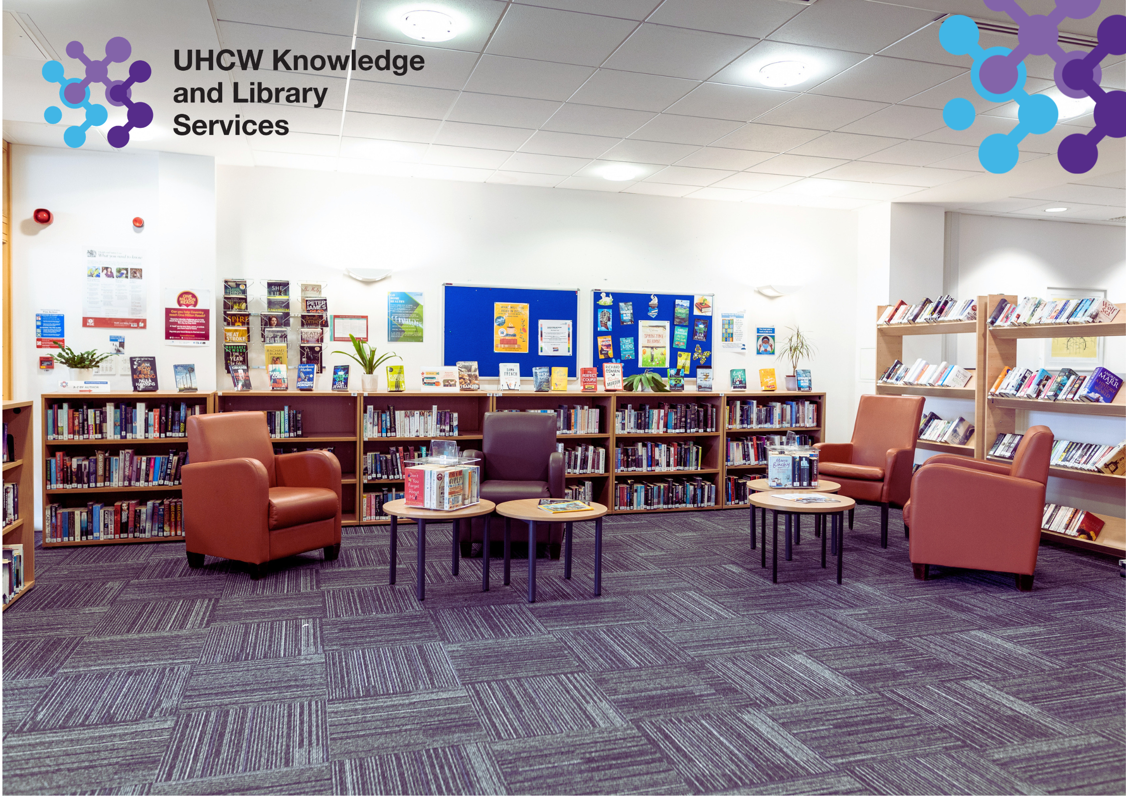 Photograph of wellbeing area of UHCW library, including comfortable armchairs and fiction books.