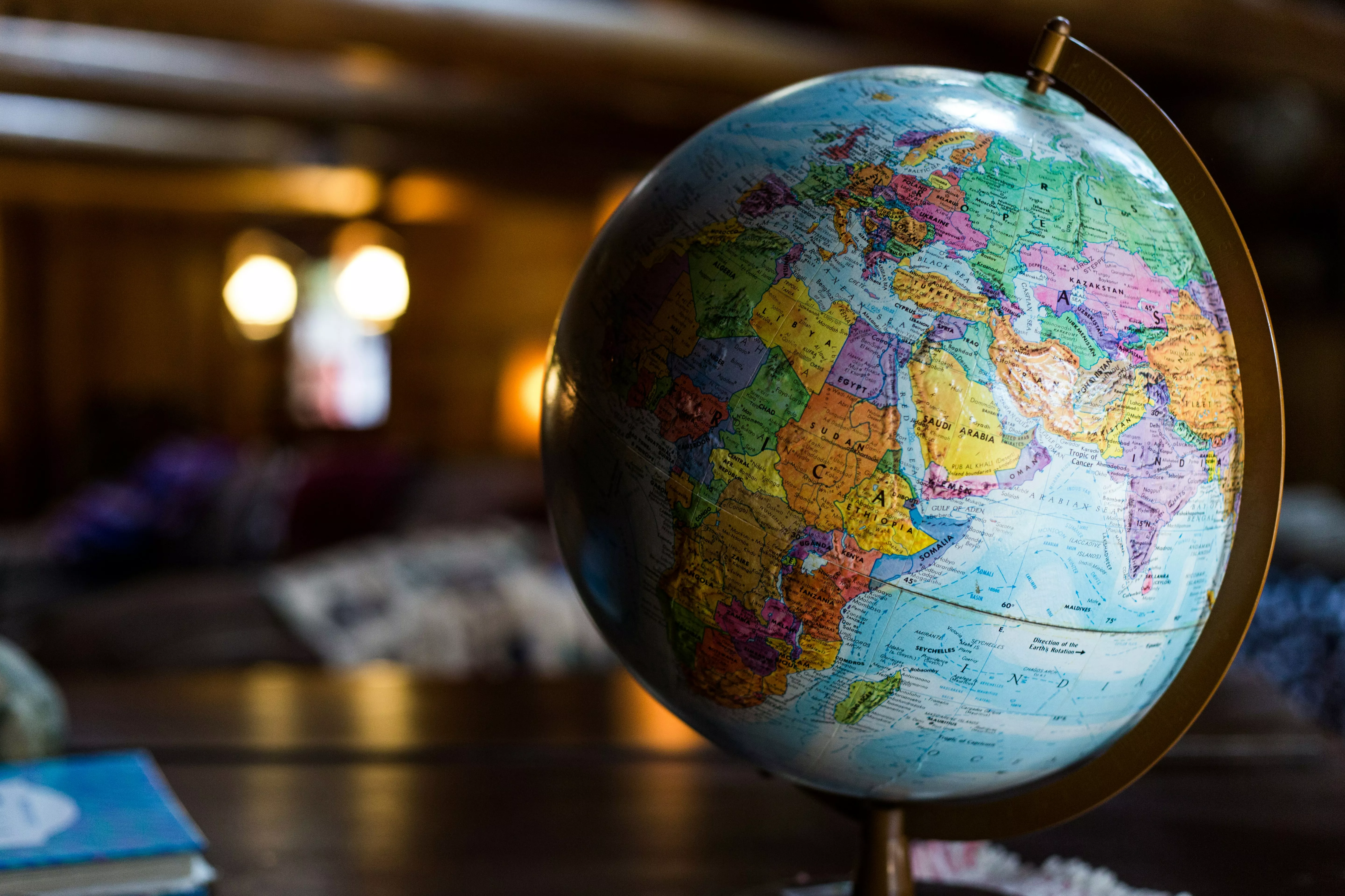 Image of a globe in focus in the foreground. Background is an out of focus, dark room.